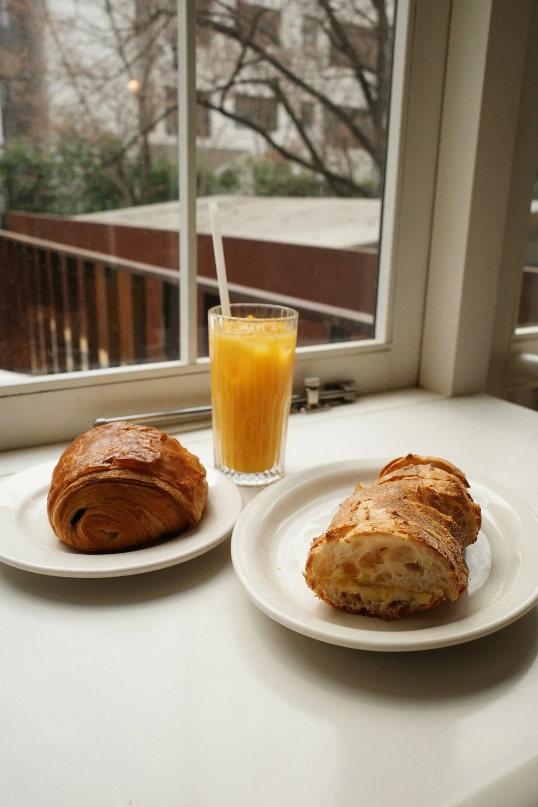 Croissant, sliced bread and orange juice on a windowsill