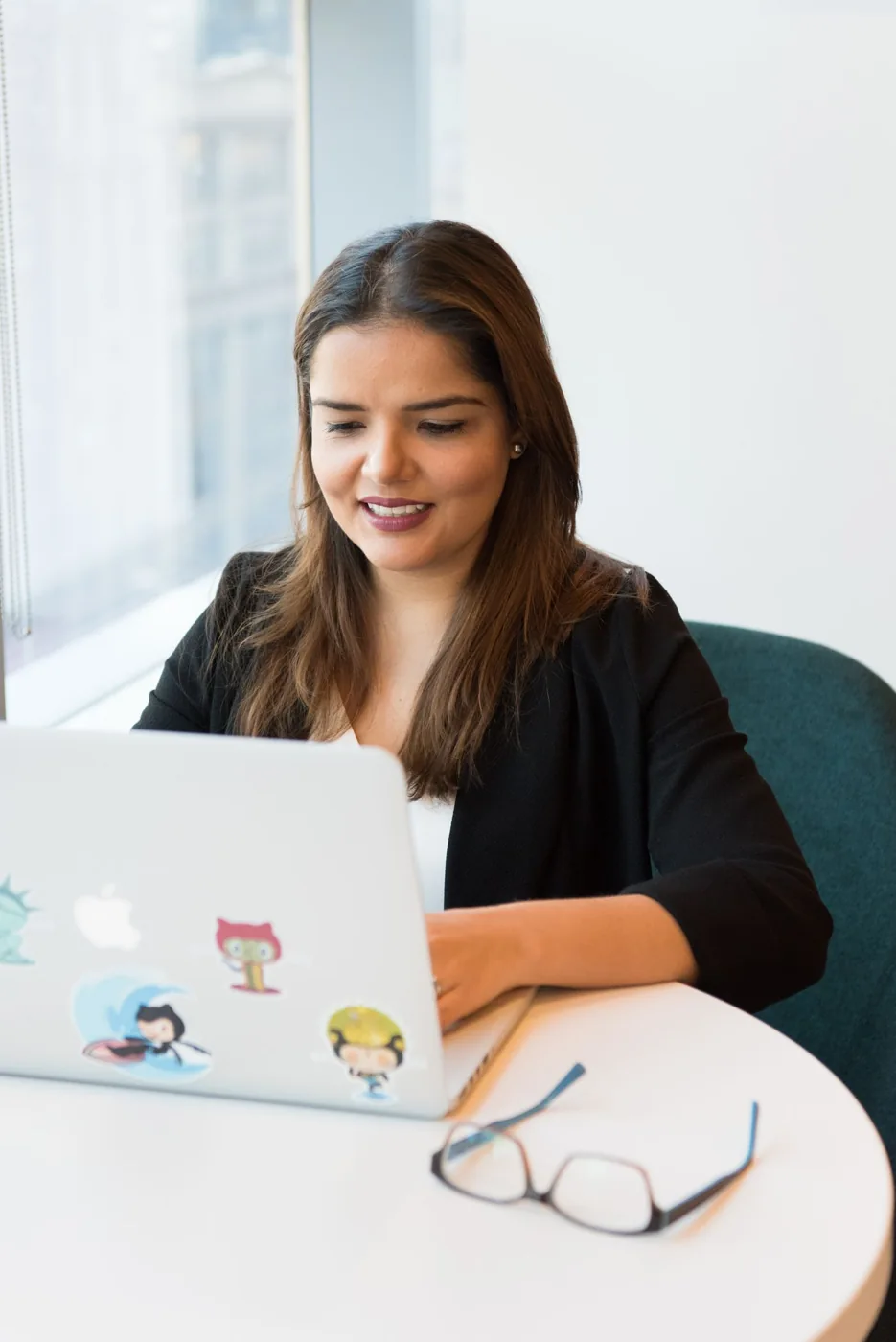 Woman in a black blazer working at a laptop in an office