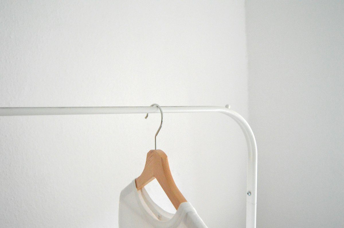 White shirt on a wooden hanger against a light wall