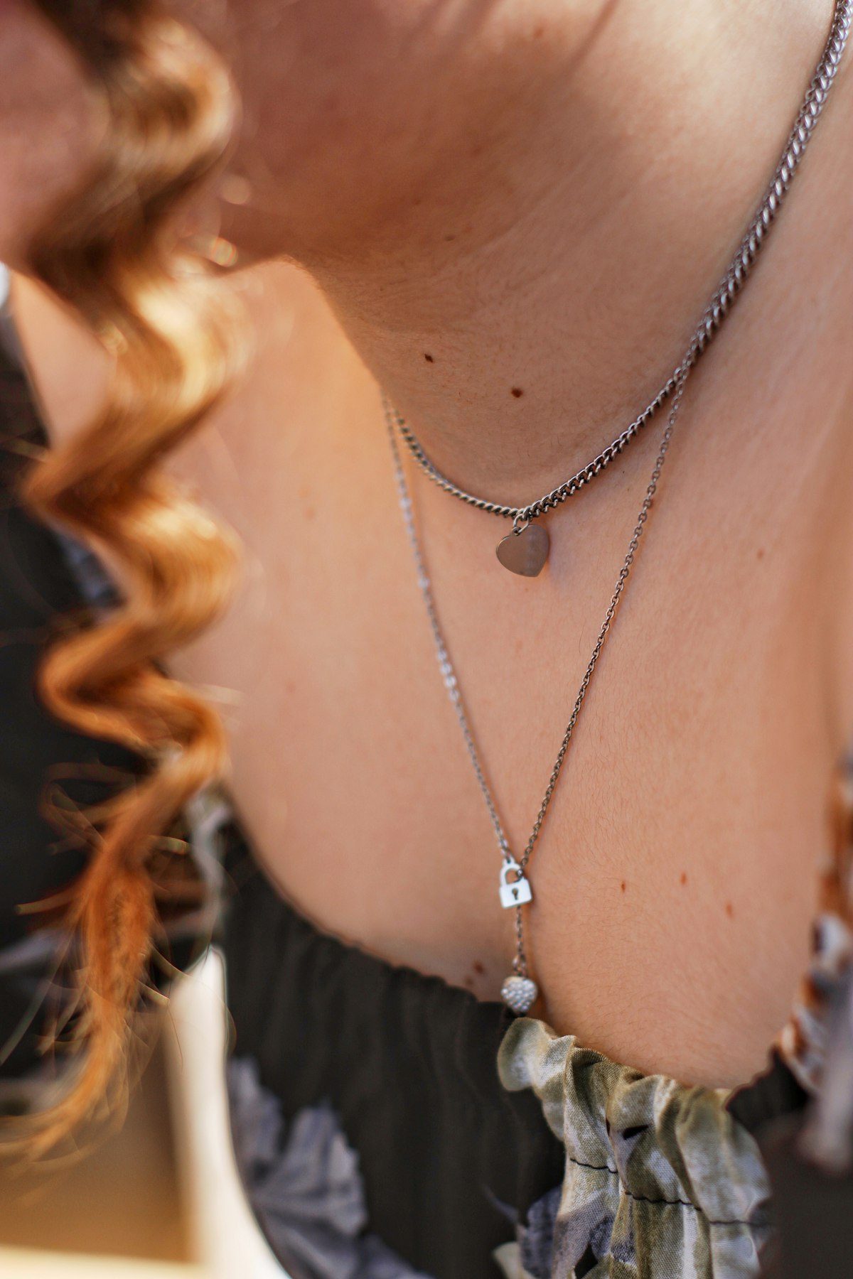 Layered necklaces worn above a dark neckline.