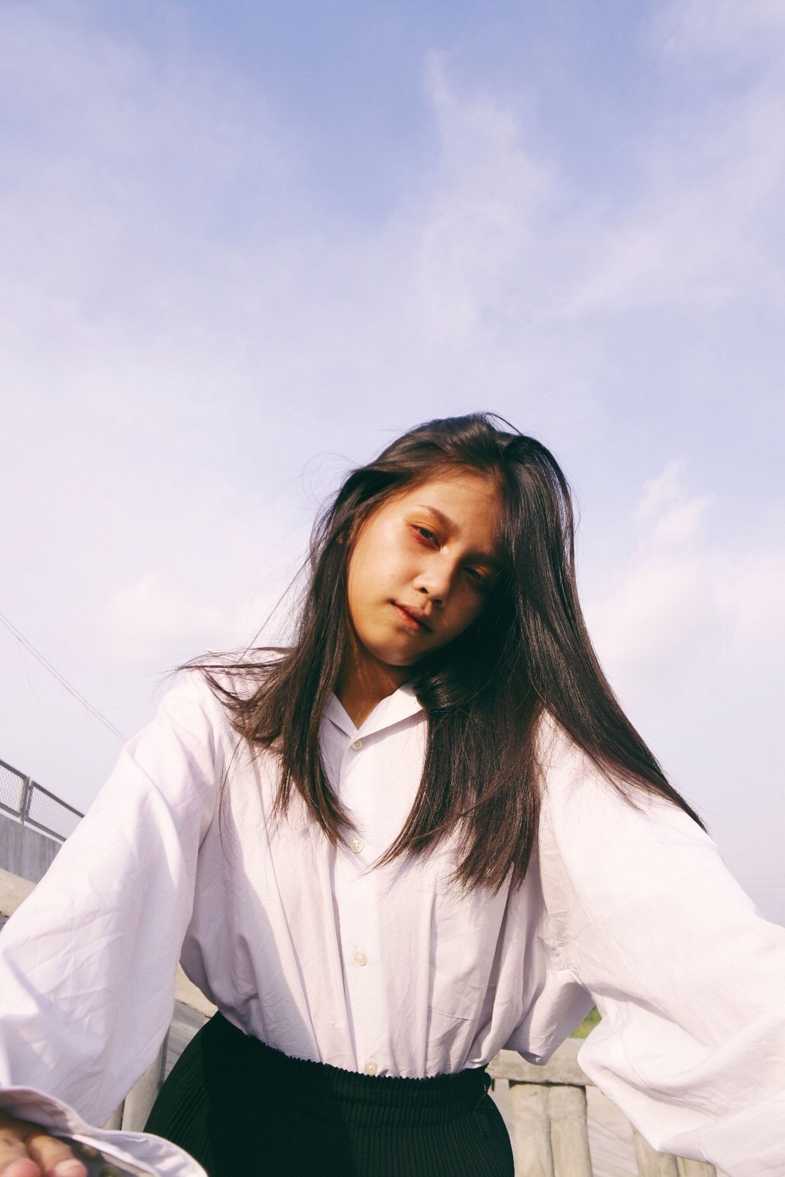 A woman wearing a white short-sleeved top outdoors.