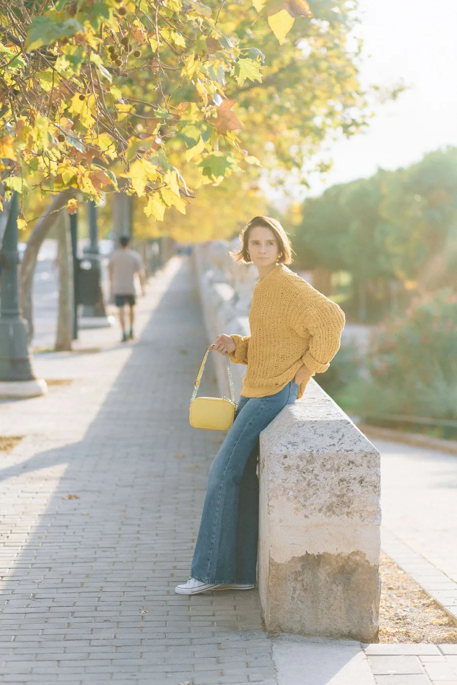 Woman wearing a knitted sweater and jeans on a sunny street